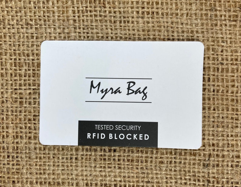 May include: White card with black text that reads "Myra Bag" and "TESTED SECURITY RFID BLOCKED".