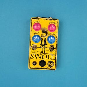May include: A yellow effects pedal with pink and blue knobs, featuring a cartoon weightlifter graphic and the word "SWOLE." The pedal has the words "AFTER," "BEFORE," "SIZE," and "WEIGHT" printed on it. The pedal is on a blue background.