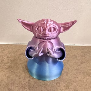 K&ouml;nnte beinhalten: Eine 3D-gedruckte Figur eines beliebten Charakters aus dem Star Wars-Franchise. Die Figur h&auml;lt eine kleine Kugel in ihren H&auml;nden. Die Figur ist in einem Farbverlauf von Pink und Blau bemalt.
