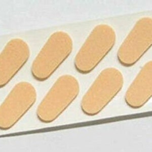 May include: A sheet of eight beige, oval-shaped adhesive pads for glasses.