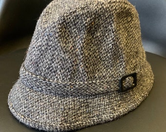 Könnte beinhalten: Ein grauer Tweed-Bucket-Hut mit einer schwarzen Schnalle an der Seite.