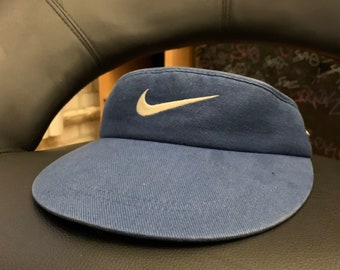 Könnte beinhalten: Ein blauer Visier mit einem weißen Nike-Swoosh-Logo.