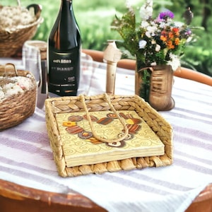 May include: A woven wicker napkin holder with a yellow and brown patterned napkin inside. The holder is on a white and gray striped tablecloth.