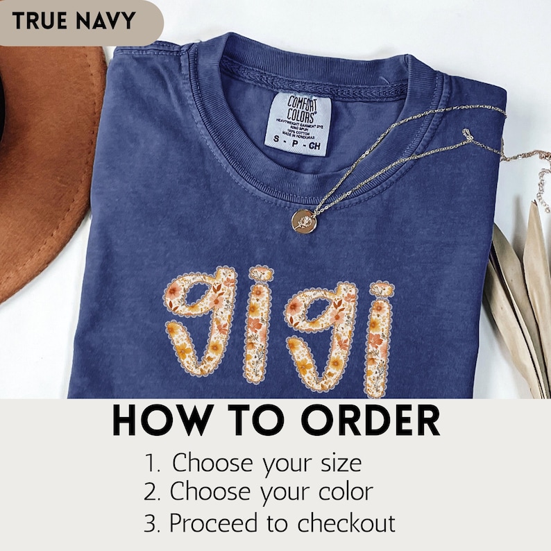 Op de afbeelding: Een marineblauw t-shirt met het woord "gigi" in een bloemenpatroon. De shirt heeft een ronde hals en korte mouwen. De tekst "TRUE NAVY" staat linksboven. De tekst "HOW TO ORDER" staat onderaan, met instructies.