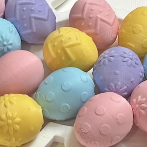 Puede incluir: Una colección de huevos de Pascua de color pastel con varios patrones en relieve, incluyendo lunares, flores y diseños geométricos.