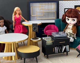 May include: A collection of miniature dollhouse furniture including a teal sofa, a pink sofa, round tables with gold bases and white tops, a black record player console, a small black stool, a pink chair, and several dolls in various outfits.