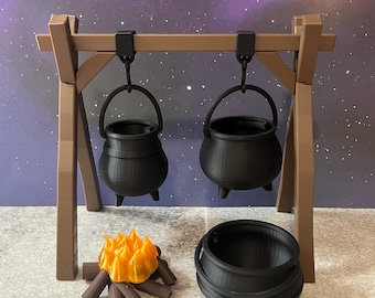May include: A miniature black cauldron set, including two hanging cauldrons, a ground cauldron, and a small campfire. The cauldrons are suspended from a brown wooden frame. The campfire has orange flames and brown logs.