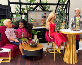 May include: A miniature lounge scene featuring four dolls. Two dolls sit on a magenta sofa next to a round coffee table with a bowl of spheres. A doll in a red dress sits on a magenta stool at a round table with a gold base. A doll stands nearby.