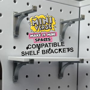 Puede incluir: Un tablero perforado blanco con soportes de estante grises y un estante blanco. La imagen incluye el texto "MGA's Mini Verse Make It Mini Spaces Compatible Shelf Brackets."