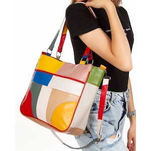May include: A colourful patchwork tote bag with a long strap. The bag is made of different coloured leather pieces, including red, yellow, blue, green, and white.