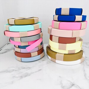May include: A stack of colorful fabric rolls with brown paper wrapping. The rolls are arranged in two stacks, one on the left and one on the right. The rolls are in various colors, including pink, blue, yellow, and green.