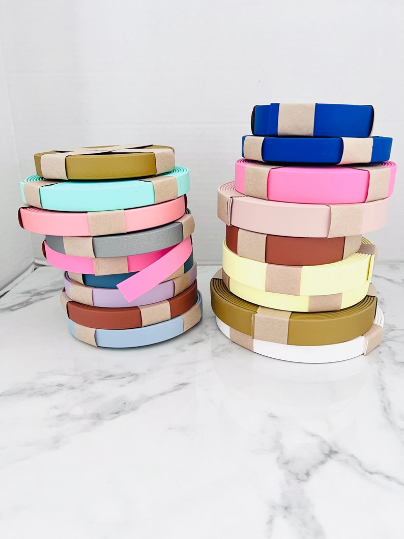 May include: A stack of colorful fabric rolls with brown paper wrapping. The rolls are arranged in two stacks, one on the left and one on the right. The rolls are in various colors, including pink, blue, yellow, and green.