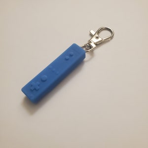 May include: A blue silicone keychain shaped like a Nintendo Wii remote.