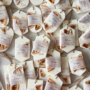 Personalized burnt orange soy wax sachet favors featuring dried orange slices, handmade soy wax air fresheners and custom vellum labels with names and dates. Elegant wedding favors, bridal shower favors, baby shower gifts, engagement party favors and wedding guest favors. Neutral boho decor with natural botanicals and premium fragrance oils. Perfect for wedding welcome bags, bridesmaid gifts, bridal events and special celebrations.