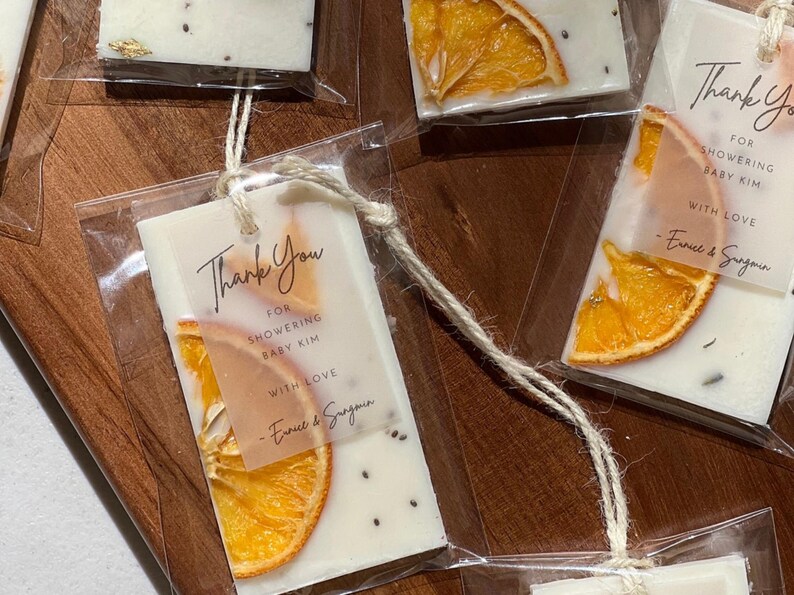 Personalized burnt orange soy wax sachet favors featuring dried orange slices, handmade soy wax air fresheners and custom vellum labels with names and dates. Elegant wedding favors, bridal shower favors, baby shower gifts, engagement party favors and wedding guest favors. Neutral boho decor with natural botanicals and premium fragrance oils. Perfect for wedding welcome bags, bridesmaid gifts, bridal events and special celebrations.