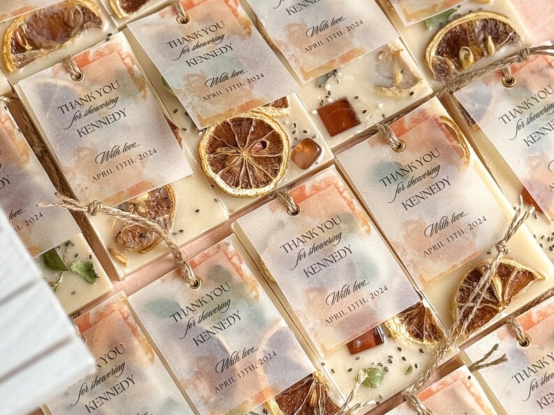 Personalized burnt orange soy wax sachet favors featuring dried orange slices, handmade soy wax air fresheners and custom vellum labels with names and dates. Elegant wedding favors, bridal shower favors, baby shower gifts, engagement party favors and wedding guest favors. Neutral boho decor with natural botanicals and premium fragrance oils. Perfect for wedding welcome bags, bridesmaid gifts, bridal events and special celebrations.