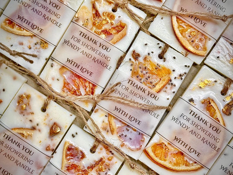 Personalized burnt orange soy wax sachet favors featuring dried orange slices, handmade soy wax air fresheners and custom vellum labels with names and dates. Elegant wedding favors, bridal shower favors, baby shower gifts, engagement party favors and wedding guest favors. Neutral boho decor with natural botanicals and premium fragrance oils. Perfect for wedding welcome bags, bridesmaid gifts, bridal events and special celebrations.