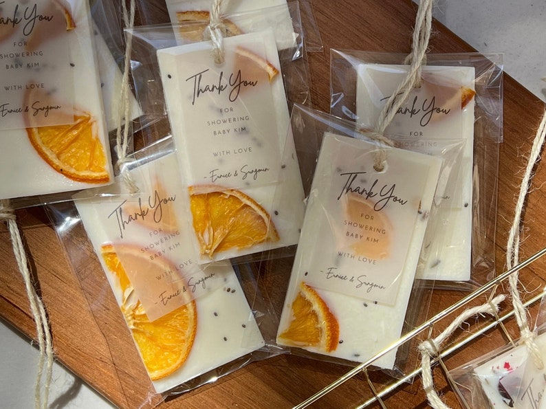 Personalized burnt orange soy wax sachet favors featuring dried orange slices, handmade soy wax air fresheners and custom vellum labels with names and dates. Elegant wedding favors, bridal shower favors, baby shower gifts, engagement party favors and wedding guest favors. Neutral boho decor with natural botanicals and premium fragrance oils. Perfect for wedding welcome bags, bridesmaid gifts, bridal events and special celebrations.
