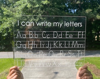 May include: A clear plastic dry-erase board with the text "I can write my letters" at the top. The alphabet is written in rows with dotted lines for tracing.