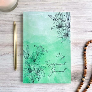 May include: A green watercolor journal with black floral illustrations and the text "My Engagement Journal".