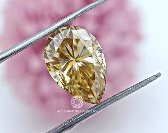 May include: A pear-shaped, golden-yellow diamond is held by silver tweezers against a soft pink and white background. The diamond's facets reflect light, creating a starburst effect. The text "4CS DIAMOND JEWELRY" is visible at the bottom.