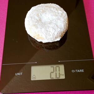 Puede incluir: Una dona blanca en polvo sobre una b&aacute;scula de cocina digital negra. La b&aacute;scula marca 2,0 fl oz.