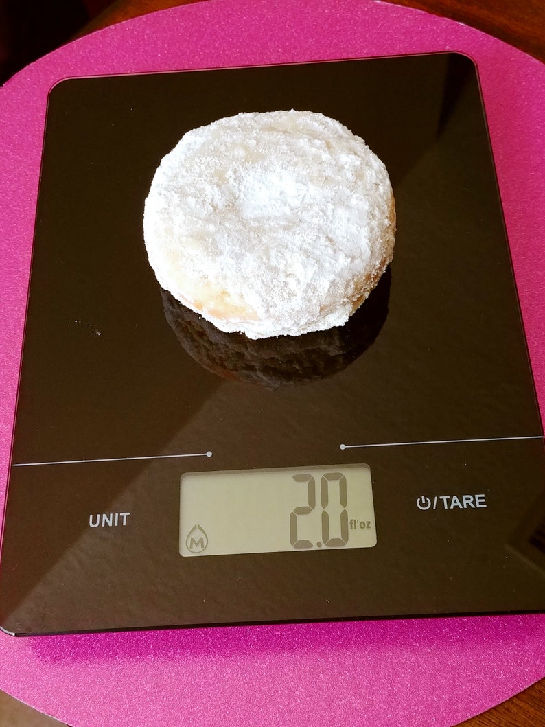 Puede incluir: Una dona blanca en polvo sobre una b&aacute;scula de cocina digital negra. La b&aacute;scula marca 2,0 fl oz.