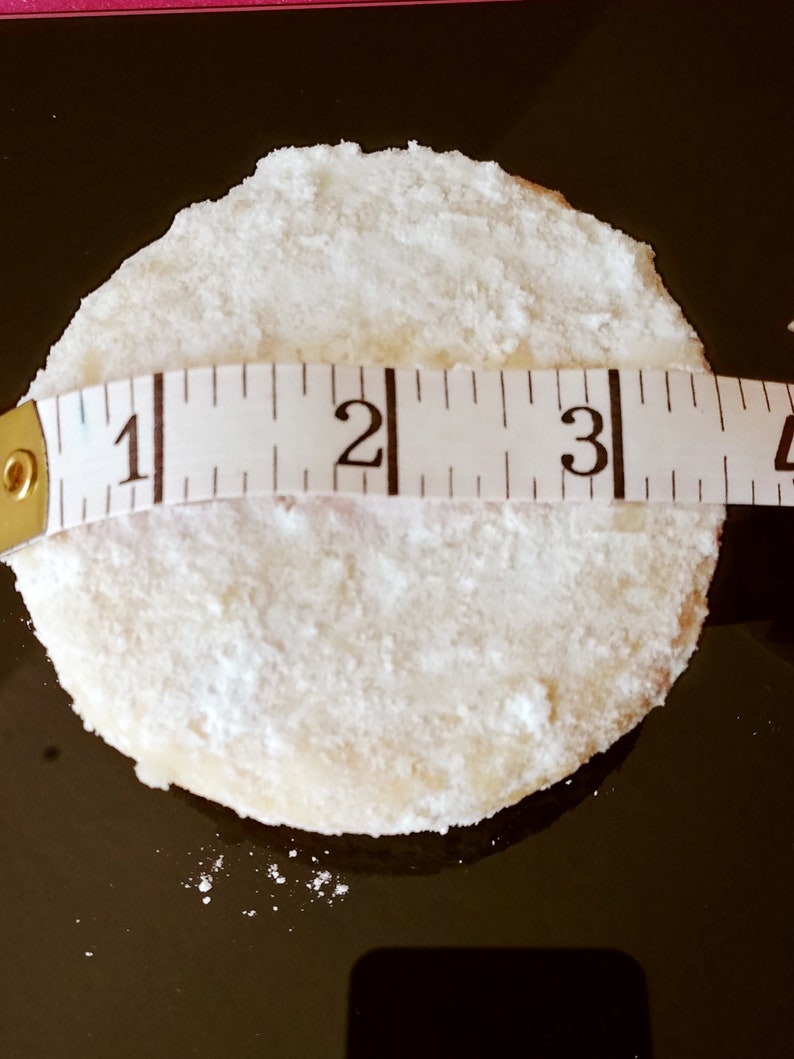 Puede incluir: Una galleta redonda blanca espolvoreada con az&uacute;car glas, medida con una cinta m&eacute;trica que muestra 7,6 cm de di&aacute;metro.