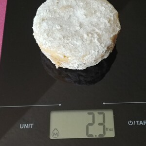 Puede incluir: Una galleta redonda, blanca y en polvo sobre una b&aacute;scula de cocina digital negra. La b&aacute;scula marca 2,3 fl oz.