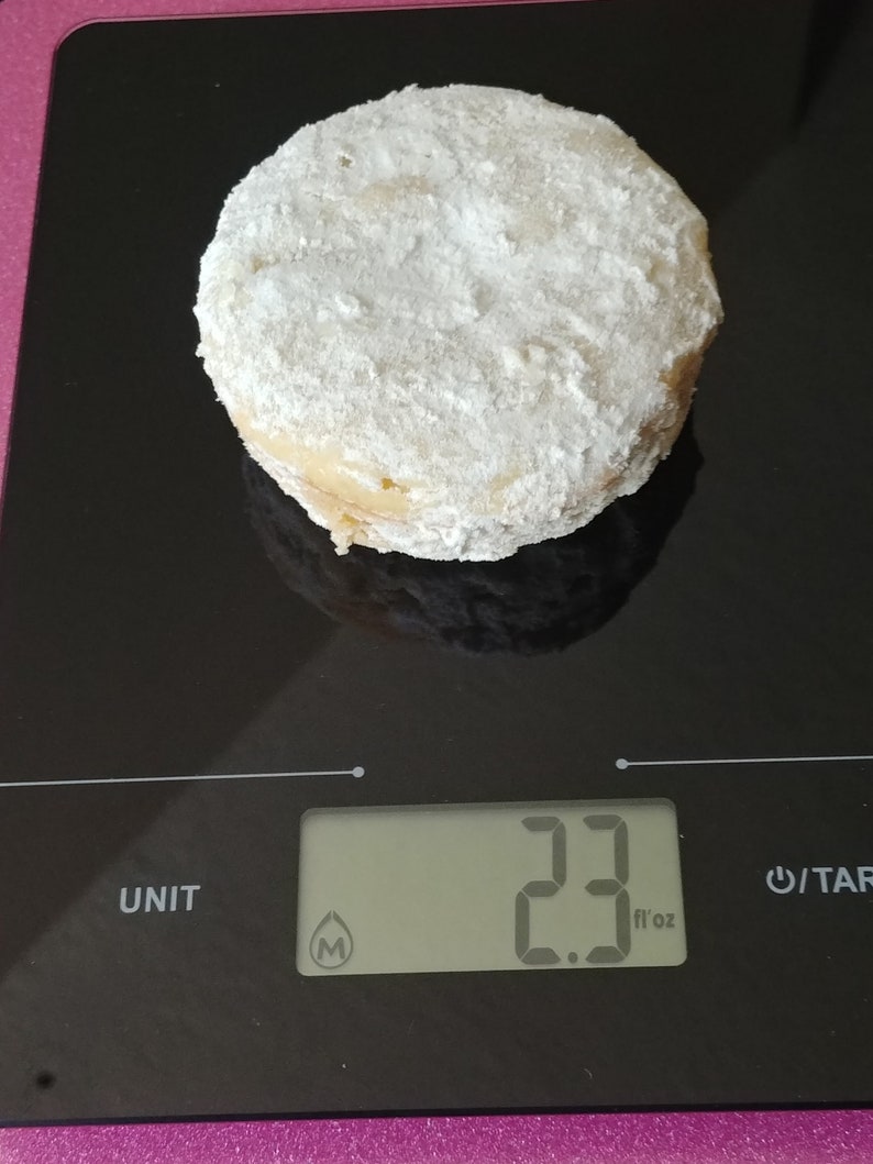 Puede incluir: Una galleta redonda, blanca y en polvo sobre una b&aacute;scula de cocina digital negra. La b&aacute;scula marca 2,3 fl oz.