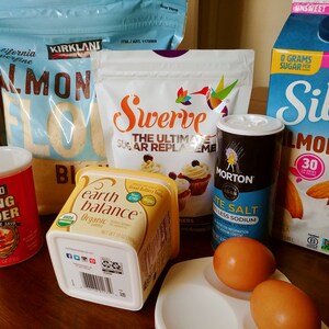 Puede incluir: Una colecci&oacute;n de ingredientes para hornear que incluye harina de almendras, polvo para hornear, mantequilla, sustituto del az&uacute;car, sal, leche de almendras y huevos.