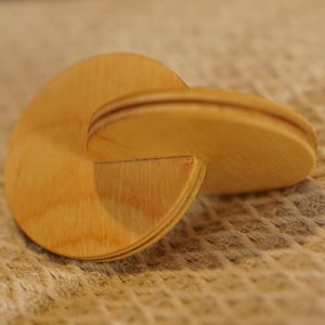 May include: A wooden puzzle made of two interlocking pieces, each shaped like a spiral. The puzzle is made of light brown wood and has a smooth, polished finish.