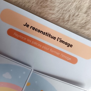 K&ouml;nnte beinhalten: Nahaufnahme einer Puzzlebox mit franz&ouml;sischem Text. Der Text lautet "Je reconstitue l'image" und "Replace les pi&egrave;ces pour former l'image". Die Box hat ein pfirsichfarbenes und orangefarbenes Design.
