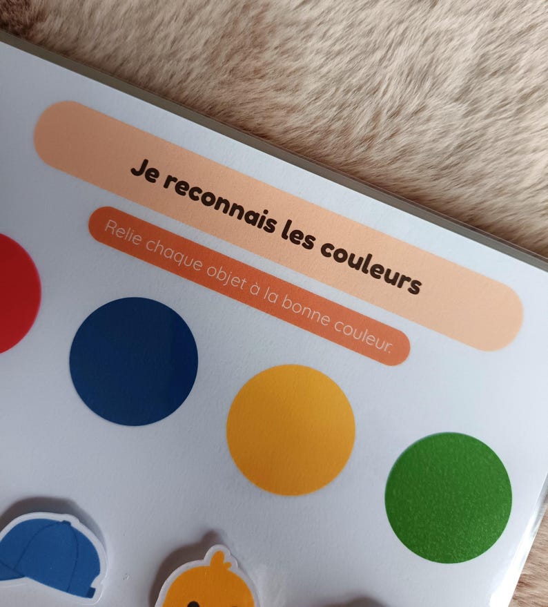 K&ouml;nnte beinhalten: Ein farbenfrohes Lernspiel mit dem Text "Je reconnais les couleurs" und "Relie chaque objet &agrave; la bonne couleur." Das Spiel zeigt rote, blaue, gelbe und gr&uuml;ne Kreise sowie Illustrationen von Objekten.