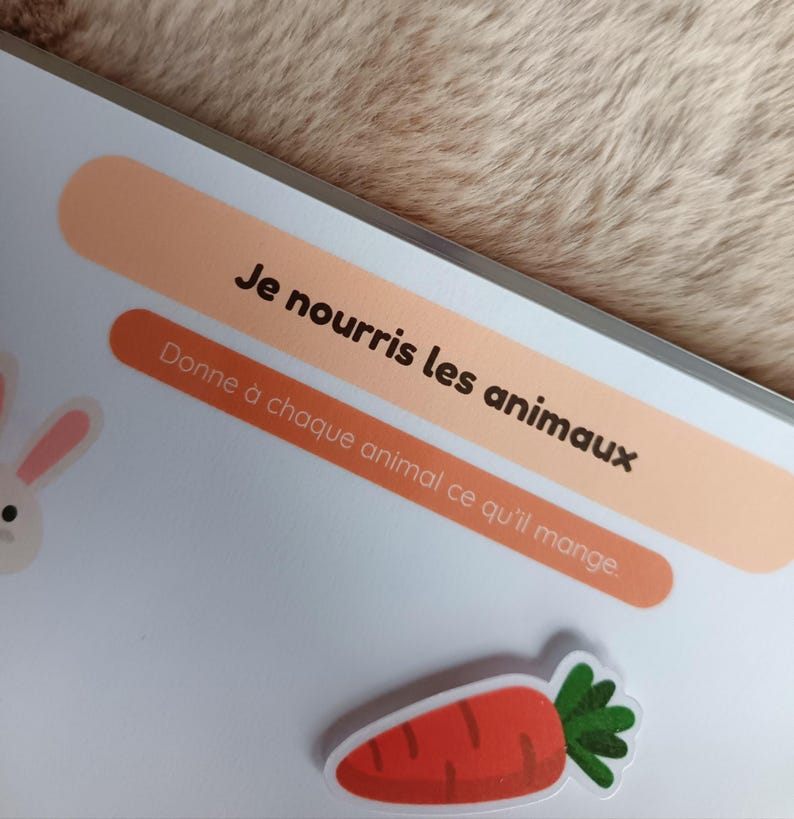 K&ouml;nnte beinhalten: Ein Kinder-Lehrbuch mit dem Text "Je nourris les animaux" und "Donne &agrave; chaque animal ce qu'il mange." Ein Karottenaufkleber und ein Cartoon-Kaninchen sind ebenfalls zu sehen.