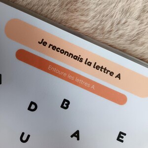 K&ouml;nnte beinhalten: Ein wei&szlig;es Arbeitsblatt mit dem Text "Je reconnais la lettre A" und "Entoure les lettres A." Das Arbeitsblatt enth&auml;lt die Buchstaben D, B, U, A und E. Der Hintergrund ist hellbraun.
