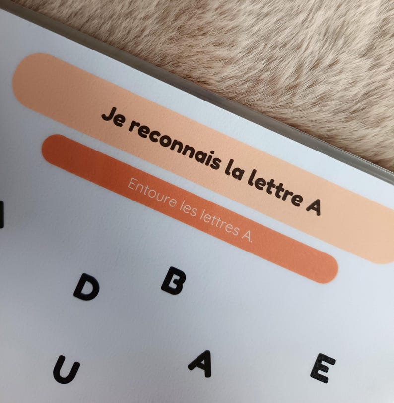 K&ouml;nnte beinhalten: Ein wei&szlig;es Arbeitsblatt mit dem Text "Je reconnais la lettre A" und "Entoure les lettres A." Das Arbeitsblatt enth&auml;lt die Buchstaben D, B, U, A und E. Der Hintergrund ist hellbraun.