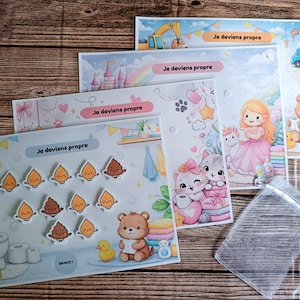 Può includere: Un set di schede didattiche per bambini con il testo "Je deviens propre" (Mi sto pulendo). Le schede presentano illustrazioni di una principessa, gattini, un orso e una scena di costruzione. Include un sacchetto di plastica trasparente.