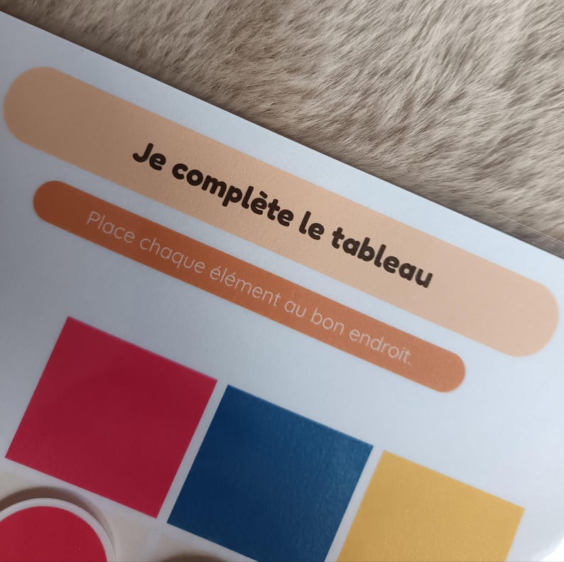 K&ouml;nnte beinhalten: Ein farbenfrohes Lernspiel mit dem Text "Je compl&egrave;te le tableau" und "Place chaque &eacute;l&eacute;ment au bon endroit." Das Spiel zeigt rote, blaue und gelbe geometrische Formen. Der Hintergrund ist hellbraun.