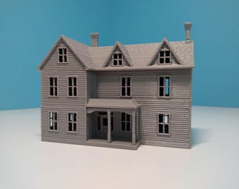 May include: A gray 3D printed model of a two-story house with a porch. The house has multiple windows and a chimney.
