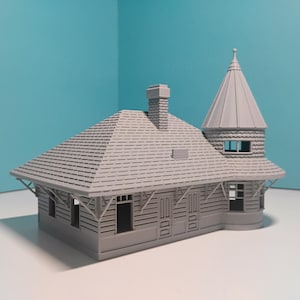 Puede incluir: Modelo gris de un edificio con tejado inclinado, chimenea y torre. El edificio tiene ventanas y puertas, y probablemente sea una miniatura de una estación de tren o estructura similar.