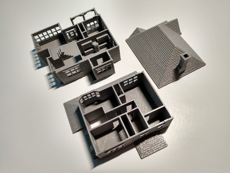 Puede incluir: Un modelo de casa impreso en 3D, separado en tres piezas: el techo, el primer piso y el segundo piso. El modelo es gris y muestra la distribuci&oacute;n interior de la casa.