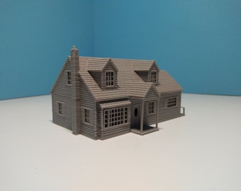 Puede incluir: Un modelo de casa pequeña de color gris impreso en 3D con un techo a dos aguas, dos ventanas de buhardilla y un porche delantero.
