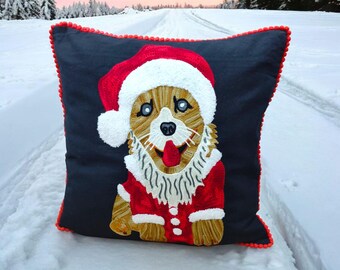 Può includere: Un cuscino natalizio nero e rosso con un'immagine ricamata di un cane che indossa un cappello di Babbo Natale e un costume di Babbo Natale rosso e bianco.