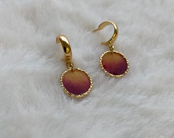 May include: A pair of gold-coloured hoop earrings. Each earring has a circular pendant with a colour gradient, shifting from yellow to deep red. The pendant edges have a textured, gold-coloured border.