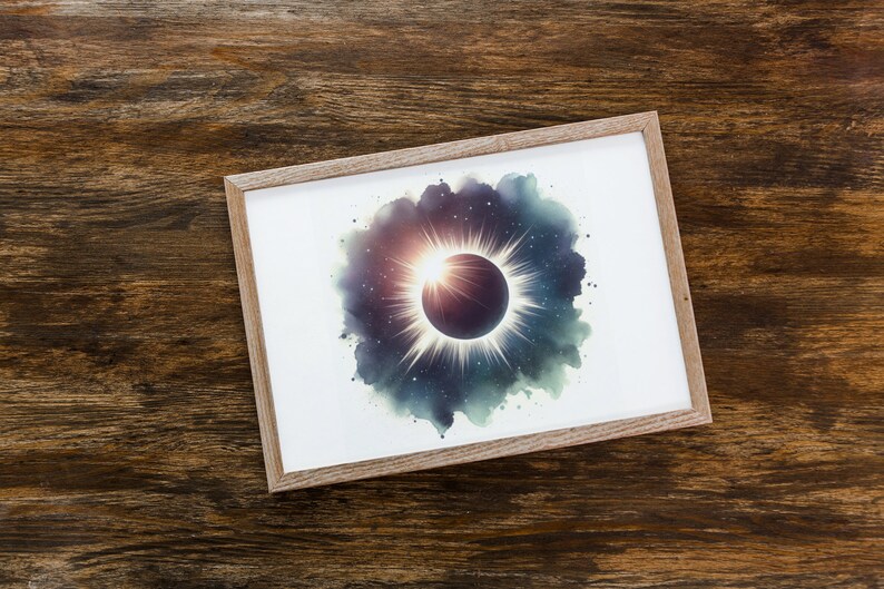 May include: A framed print of a watercolour painting depicting a solar eclipse. The eclipse is surrounded by a dark blue and green watercolour cloud with white stars. The sun is shining brightly behind the moon, creating a halo of light.