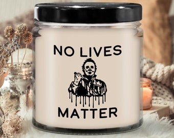 May include: A white candle with a black lid and a black graphic of a horror movie character with the text "NO LIVES MATTER" on a white background.
