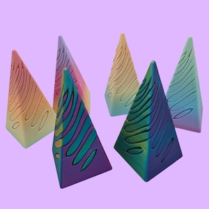 May include: Set of six colorful geometric pyramid-shaped decorative objects. Each pyramid has a different gradient color and a wavy pattern.