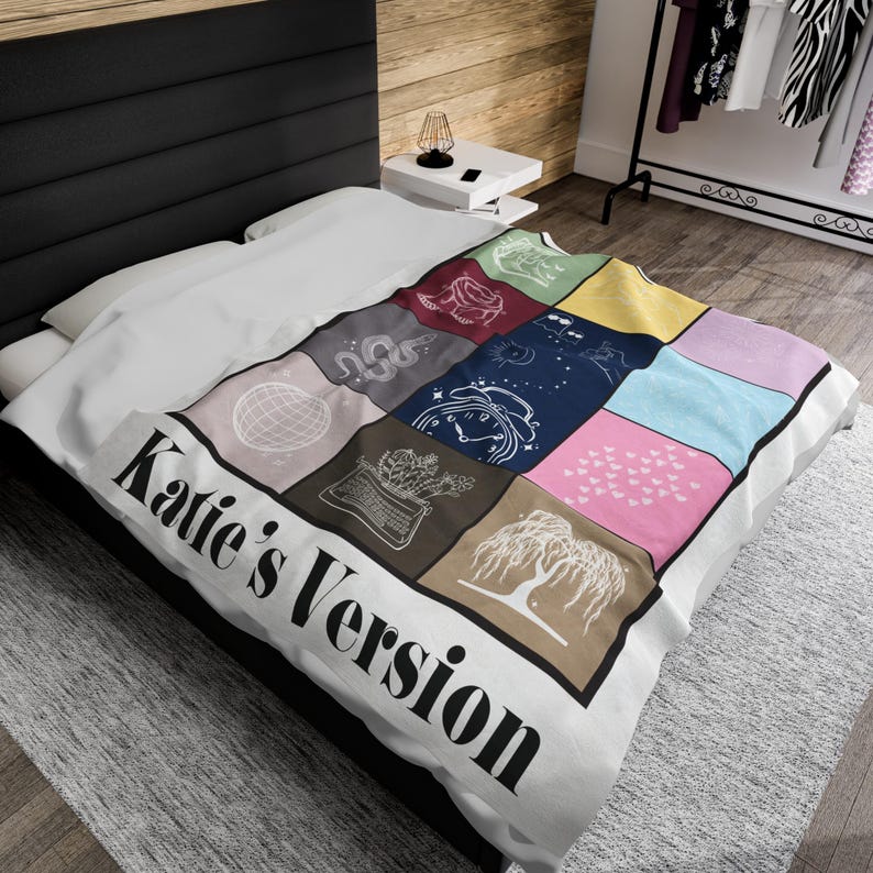 Puede incluir: Una manta blanca con un dise&ntilde;o de patchwork colorido que presenta varios s&iacute;mbolos y el texto "Katie's Version".