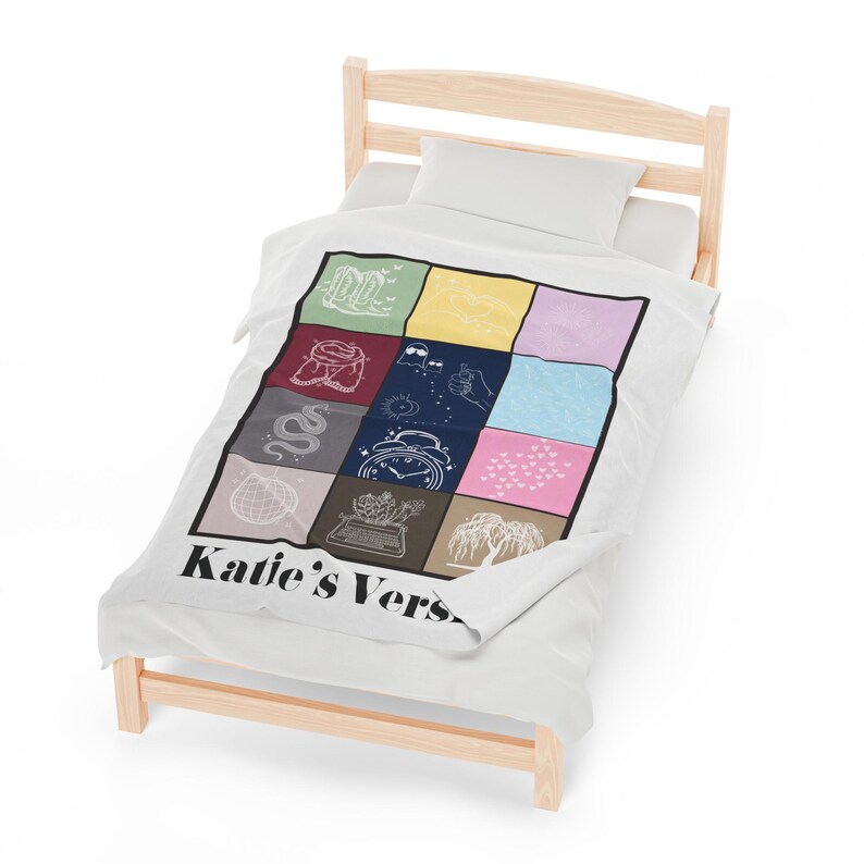 Puede incluir: Una manta blanca con un dise&ntilde;o de patchwork colorido que presenta varios s&iacute;mbolos y el texto "Katie's Verse".